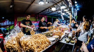 Bangkok 'taki Kasetsart Üniversitesi' nde düzenlenen 2026 Fuarı etkinliklerinde, Tayland sokak yemekleri ve oyunlarının çeşitli çeşitleri ziyaretçilere ve üniversitedeki öğrencilerin bazı gösterilerine ödül olarak sunuldu. Geniş melek lensli fotoğraf.