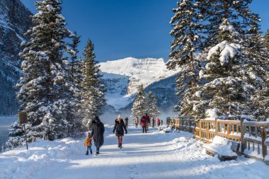 Alberta, Kanada - OCT 10 2020: Turistler kışın erken saatlerinde Louise Gölü 'nü geziyorlar. Açık mavi gökyüzü, arka planda karla kaplı dağlar. Banff Ulusal Parkı 'nın güzel manzarası.