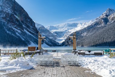 Alberta, Kanada - OCT 10 2020: Fairmont Chateau Lake Louise, güneşli bir kış sabahı. Turkuaz renkli su yüzeyinde süzülen sis. Açık mavi gökyüzü, arka planda karlı dağlar.