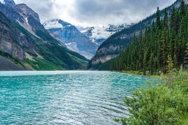Yazın güneşli bir günde Louise Gölü. Mavi gökyüzü ve beyaz bulutlar turkuaz renkli göl su yüzeyine yansıyor. Banff Ulusal Parkı 'ndaki güzel manzara, Alberta, Kanada.