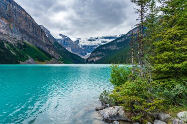 Yazın güneşli bir günde Louise Gölü. Mavi gökyüzü ve beyaz bulutlar turkuaz renkli göl su yüzeyine yansıyor. Banff Ulusal Parkı 'ndaki güzel manzara, Alberta, Kanada.