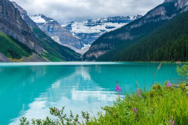 Yazın güneşli bir günde Louise Gölü. Mavi gökyüzü ve beyaz bulutlar turkuaz renkli göl su yüzeyine yansıyor. Banff Ulusal Parkı 'ndaki güzel manzara, Alberta, Kanada.
