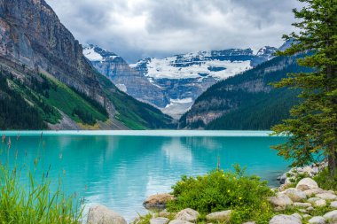 Yazın güneşli bir günde Louise Gölü. Mavi gökyüzü ve beyaz bulutlar turkuaz renkli göl su yüzeyine yansıyor. Banff Ulusal Parkı 'ndaki güzel manzara, Alberta, Kanada.