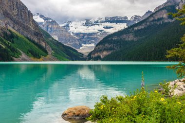 Yazın güneşli bir günde Louise Gölü. Mavi gökyüzü ve beyaz bulutlar turkuaz renkli göl su yüzeyine yansıyor. Banff Ulusal Parkı 'ndaki güzel manzara, Alberta, Kanada.