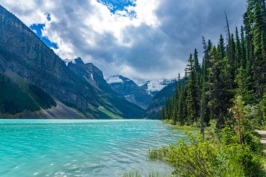 Yazın güneşli bir günde Louise Gölü. Mavi gökyüzü ve beyaz bulutlar turkuaz renkli göl su yüzeyine yansıyor. Banff Ulusal Parkı 'ndaki güzel manzara, Alberta, Kanada.