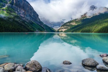 Yazın güneşli bir günde Louise Gölü. Mavi gökyüzü ve beyaz bulutlar turkuaz renkli göl su yüzeyine yansıyor. Banff Ulusal Parkı 'ndaki güzel manzara, Alberta, Kanada.