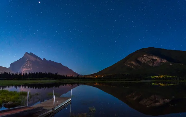 Vermilion Lakes Viewpoint at night, Full of stars above Mt Rundle, starry sky reflected in the water surface. Beautiful landscape in Banff National Park, Canadian Rockies, Alberta, Canada.