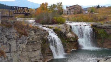 Lundbreck Şelalesi, Crowsnest Nehri 'nin sonbahar yaprakları mevsiminde bir şelalesi. Arka planda demiryolu rayları için demir bir köprü. Alberta, Kanada.