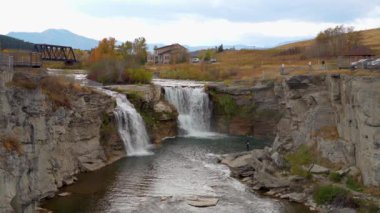 Lundbreck Şelalesi, Crowsnest Nehri 'nin sonbahar yaprakları mevsiminde bir şelalesi. Arka planda demiryolu rayları için demir bir köprü. Alberta, Kanada.