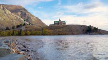 Waterton Lakes Ulusal Parkı sonbahar yeşillik mevsiminde göl kıyısı. Güneşli mavi gökyüzü ve renkli bulutlar, güzel sonbahar renk manzarası. Alberta, Kanada 'da simgeler.
