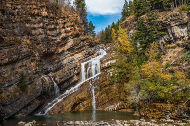 Cameron sonbahar güneşli sabahında düşer. Mavi gökyüzü, arkadaki dağların üzerinden beyaz bulutlar. Waterton Lakes Ulusal Parkı, Alberta, Kanada.