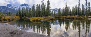 Lawrence Grassi Dağı 'nın tepesinde mavi gökyüzü ve beyaz bulutlar sonbaharda su yüzeyine yansıyor. Canmore, Canadian Rockies, Alberta, Kanada 'daki güzel doğal manzara.