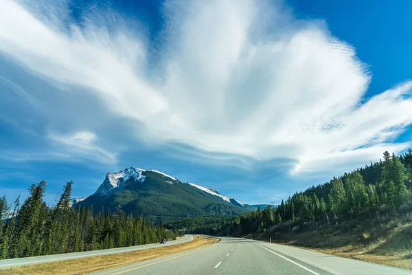 Οδήγηση στην εθνική οδό 1 (Trans-Canada Highway) το φθινόπωρο σεζόν ηλιόλουστη μέρα το πρωί. Pigeon Mountain με μπλε ουρανό και λευκά σύννεφα στο παρασκήνιο. Αλμπέρτα, Καναδάς. — Φωτογραφία Αρχείου