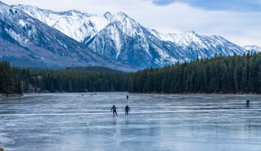 Johnson Gölü 'nde kış zamanı buz pateni yapan turistler. Arka planda karla kaplı dağ. Banff Ulusal Parkı, Kanada Kayalıkları, Alberta, Kanada.