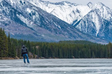 Johnson Gölü 'nde kış zamanı buz pateni yapan turistler. Arka planda karla kaplı dağ. Banff Ulusal Parkı, Kanada Kayalıkları, Alberta, Kanada.