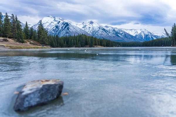 Озеро Джонсон замерзло в зимнее время. Заснеженная гора на заднем плане. Туристы здесь катаются на коньках в этом сезоне. Национальный парк Банф, Канадские Скалистые горы, Альберта, Канада. — стоковое фото