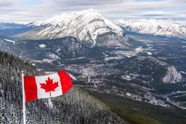 Kanada Ulusal Bayrağı, Banff Kasabası, Cascade Dağı ve kışın karla kaplı Kanada Rocky Dağları ile çevrili. Banff Ulusal Parkı, Alberta, Kanada.