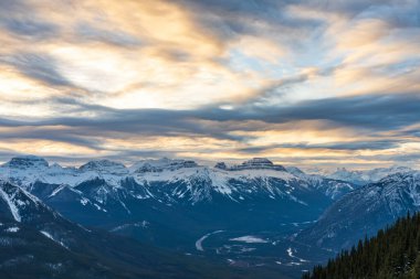 Güzel bir alacakaranlıkta kar tepeli dağ sıraları. Arka planda kırmızı pembe bulutlar var. Kışın Banff Ulusal Parkı, Kanada Kayalıkları. Güzel doğa manzarası.