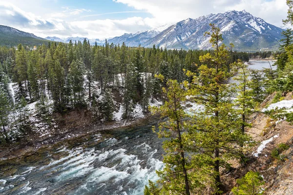 Bow River and Bow Falls in snowy autumn sunny day. View from Surprise Corner Viewpoint, Mount Norquay in the background. Banff National Park, Canadian Rockies.