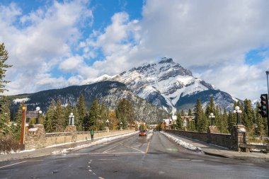 Banff, Kanada - 15: 2020 Banff Bulvarı karlı sonbahar güneşli bir günde. Arkasında beyaz bulutlar ve mavi gökyüzü olan karla kaplı Cascade Dağı. Banff Ulusal Parkı, Kanada Kayalıkları.