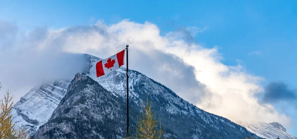 Nationalflagge von Kanada mit der Bergkette Mount Rundle an einem verschneiten, sonnigen Tag. Banff-Nationalpark, kanadische Rockies. — Stockfoto