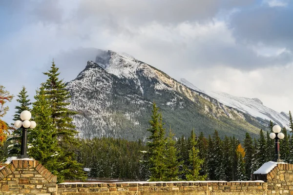 Schneebedeckte Bergkette des Mount Rundle mit verschneiten Wäldern über blauem Himmel und weißen Wolken an einem sonnigen Wintertag. Banff-Nationalpark, kanadische Rockies. — Stockfoto