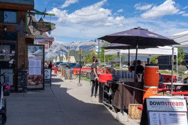 Jasper, Alberta, Kanada - 17 Haziran 2021: Covid-19 salgın döneminde yaz aylarında Jasper Kasabası sokak manzarası. İnsanlar kaldırımda oturuyor, restoranların dışında yemek yiyorlar..