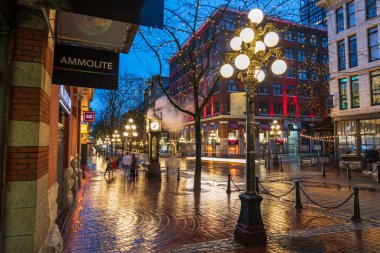 Vancouver, Kanada - MAR 21 2021: Gastown Buhar Saati ve yağmurlu bir gecede şehir merkezi güzel sokak manzarası. Cambie ve Water Caddesi..