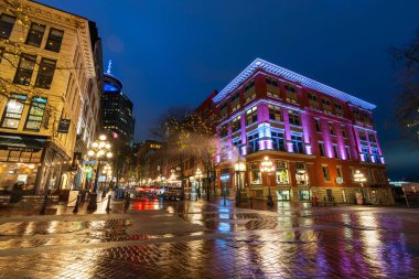 Vancouver, Kanada - MAR 21 2021: Gastown Buhar Saati ve yağmurlu bir gecede şehir merkezi güzel sokak manzarası. Cambie ve Water Caddesi..