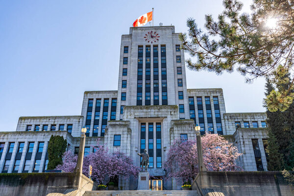 BC, Canada - March 25 2021 : Vancouver City Hall with cherry blossoms in full bloom. Canada spring time season photography.