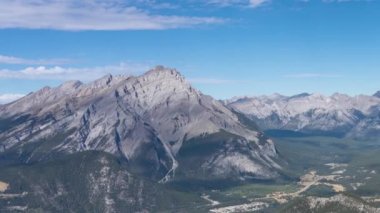Etrafı dağlarla çevrili Banff kasabası. Cascade Dağı, Minnewanka Gölü ve Girouard Dağı yaz mevsiminde güneşli bir gün. Alberta, Kanada. Zaman aşımı soldan sağa 4K UHD.