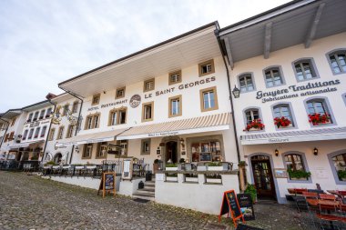 Gruyeres, Fribourg Kantonu, İsviçre - 31 Ekim 2025: Ortaçağ de Gruyeres kaldırım taşı caddesi ve tarihi taş binalar.