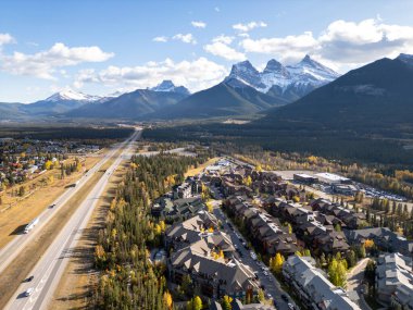 Canmore, Alberta, Canada. Aerial view of Trans-Canada Highway (Highway 1) in a autumn sunny day. The Three Sisters trio of peaks Canadian Rockies mountain range.
