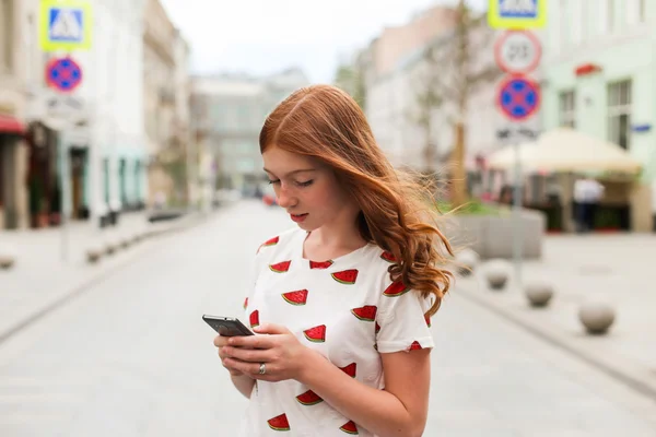 Yürüyüş ve bir akıllı telefon kullanarak bir moda mutlu kız önden görünümü