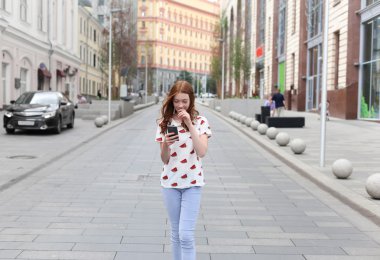 Yürüyüş ve bir akıllı telefon kullanarak bir moda mutlu kız önden görünümü