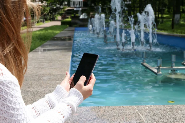 El telefon yakın çekim bir parkta tutan kız 