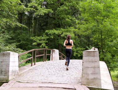 Young woman running in the summer forest. It is engaged in fitnes