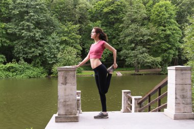 Genç kadın öğleden sonra açık havada germe.