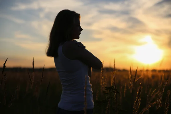 Silhouette young woman hugging herself in a wheat field.