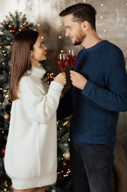 Evdeki Noel ağacının yanında şampanyaya aşık bir çift..