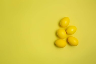 Sarı pastel arka planda, fotokopi alanı olan sarı Paskalya yumurtaları. Mutlu Paskalyalar. Minimum konsept. Moda rengi 2021.
