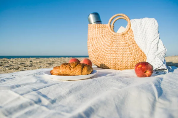 Summer picnic on the beach by the sea at a sunrise. Cozy atmosphere of summer breakfast.