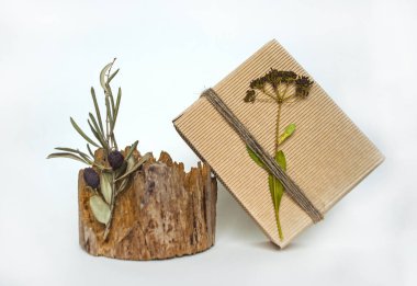 Hüner kağıdına sarılı bir hediye kutusu, sicimle eğilmiş ve güzel bir ağaç kütüğünde kurumuş bir çiçek..