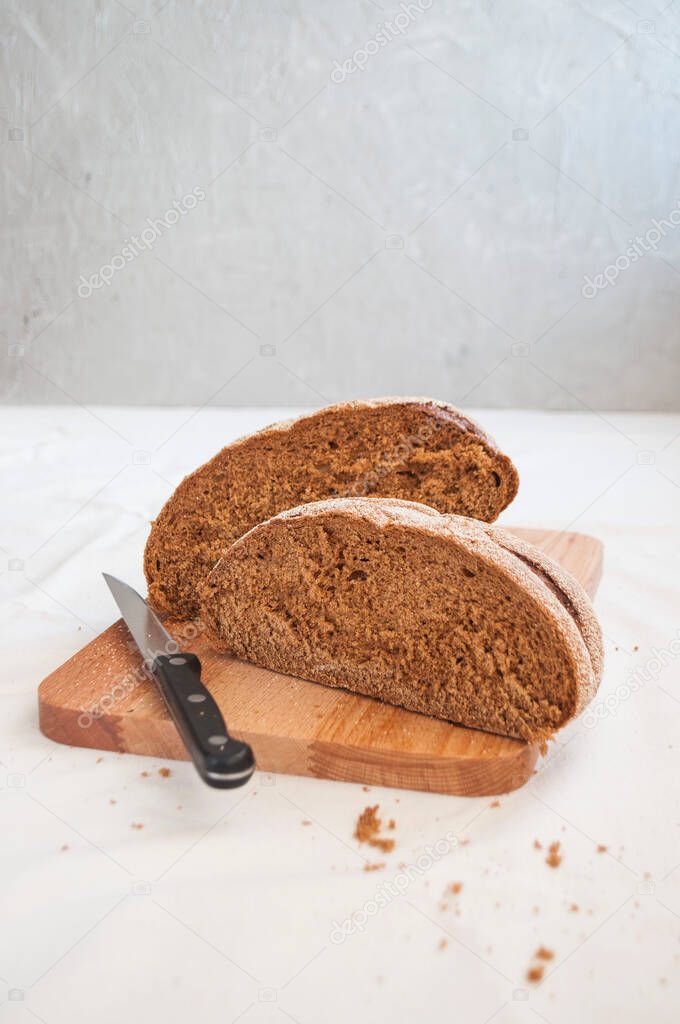 A freshly baked loaf of rye bread on a wooden cutting board. Homemade sourdough rye bread.