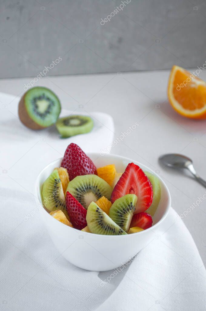 Healthy fresh delicious fruit salad with strawberries, orange, apple and kiwi. Bowl of healthy food.