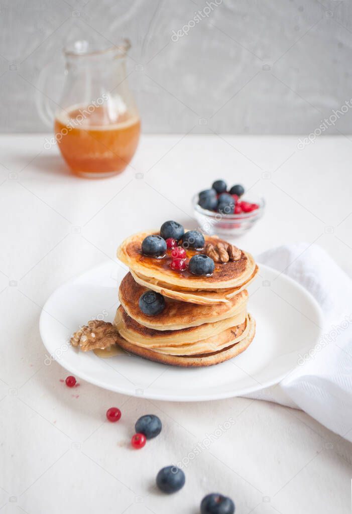 Delicious pancakes with blueberries and raspberries on a white plate.