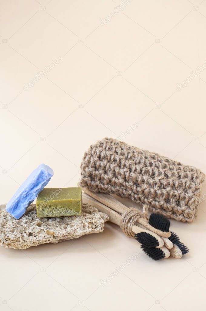 Zero waste bathroom accessories - toothbrushes, natural soap and knit twine scrubber on a beige background. Sustainable lifestyle concept.