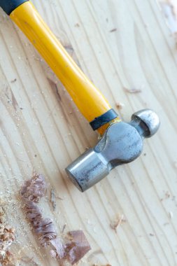 Ahşap masa üzerinde sarı demir çekiç ve odun parçaları..