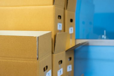 Mavi bir ofiste kahverengi kutu yığını ya da yığını.