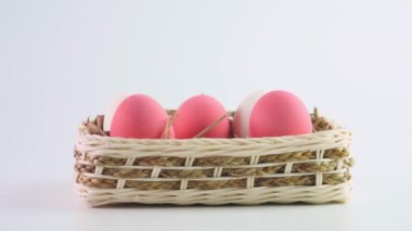 Paskalya yumurtaları beyaz ve pembe, Drop, beyaz arka planda beyaz bir sepete yerleştirilmiş ya da beyaz yumurtalarla doldurulmuş. Yavaş çekim.